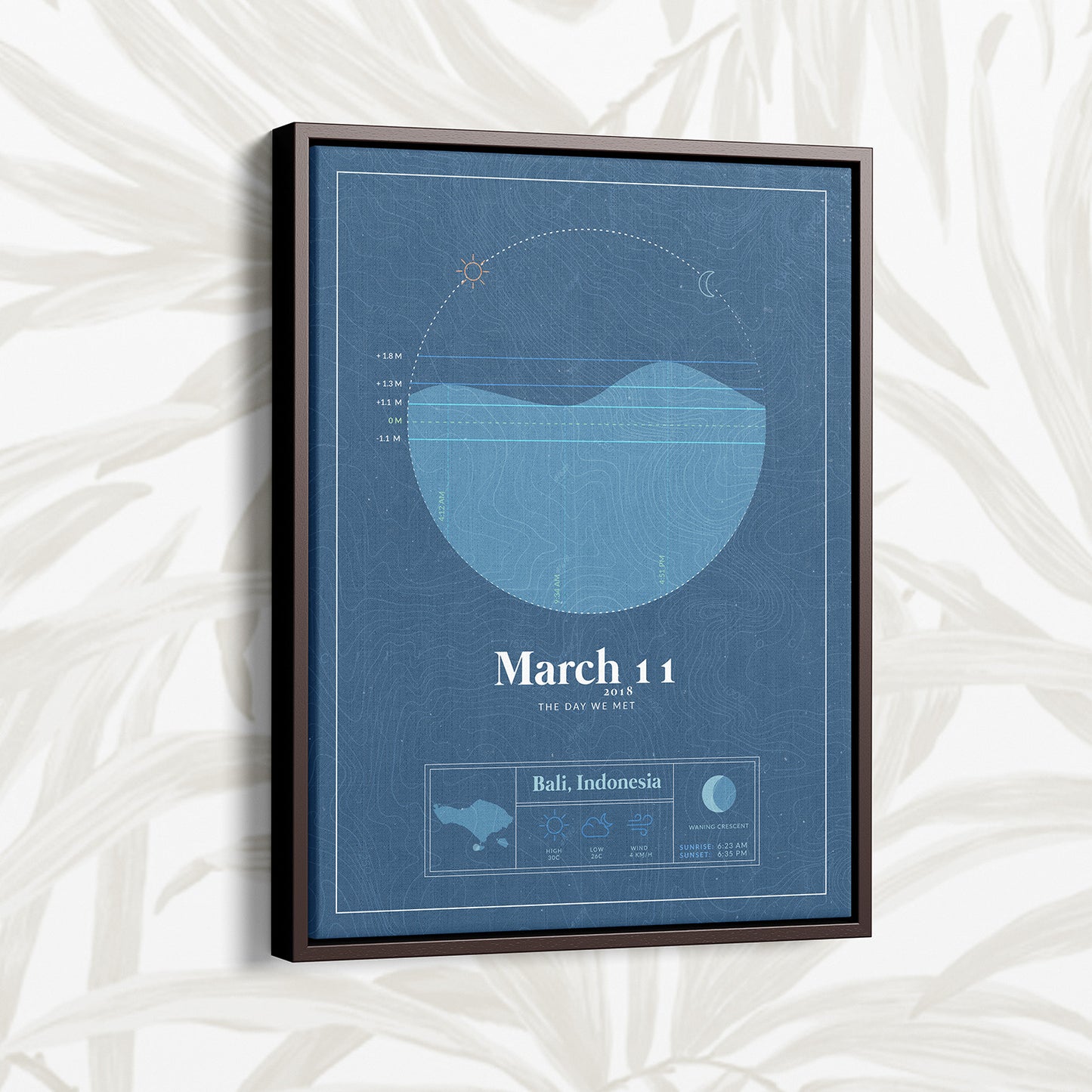 dark brown framed floating canvas of the personalized tide map by salt atlas in the vintage cobalt blue color in a home setting. These are custom posters showing the tide, weather, and moon phase for a special day, like an anniversary or birthday.