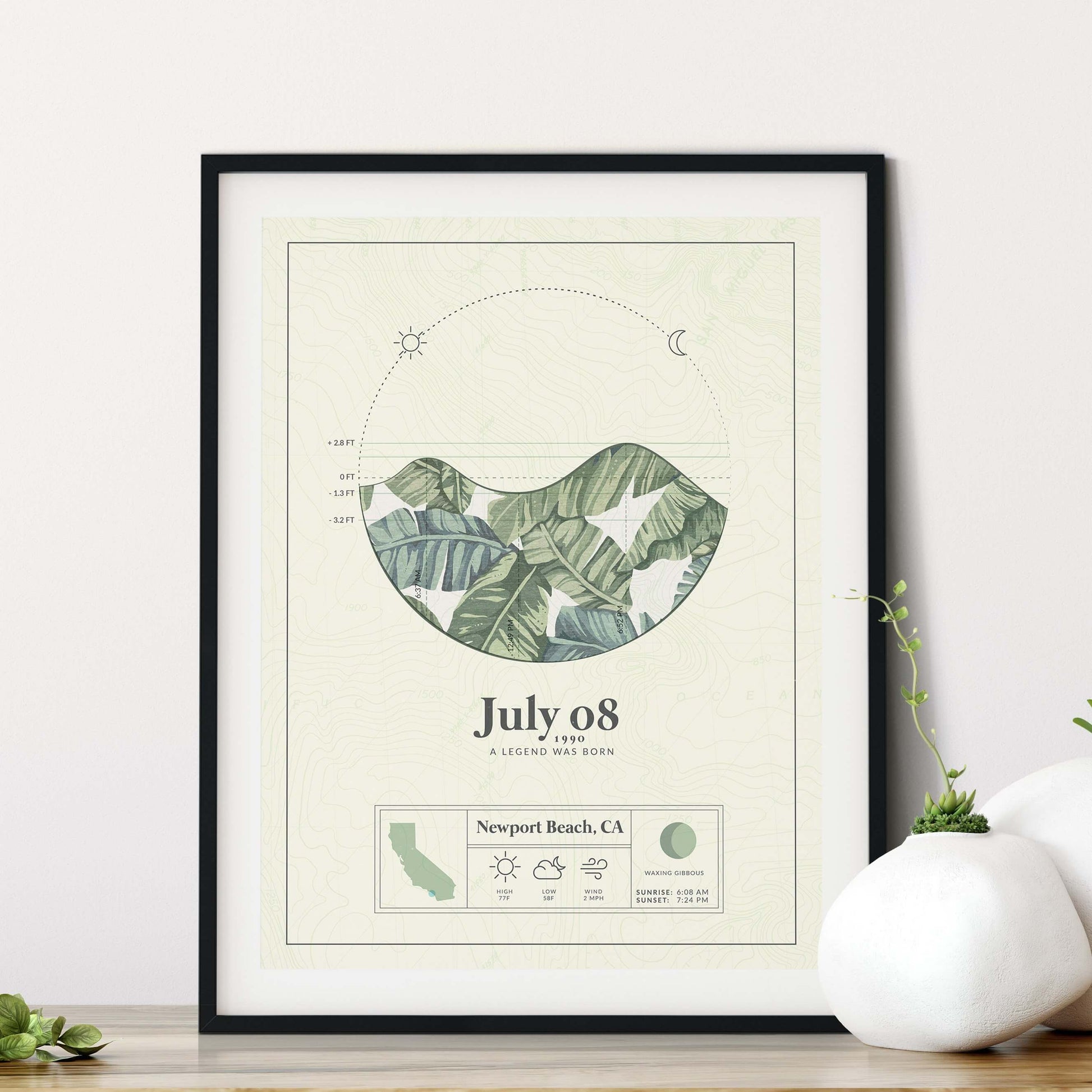 black framed picture of the personalized tide poster by salt atlas in the island green color in a home setting. These are custom posters showing the tide, weather, and moon phase for a special day, like an anniversary or birthday.